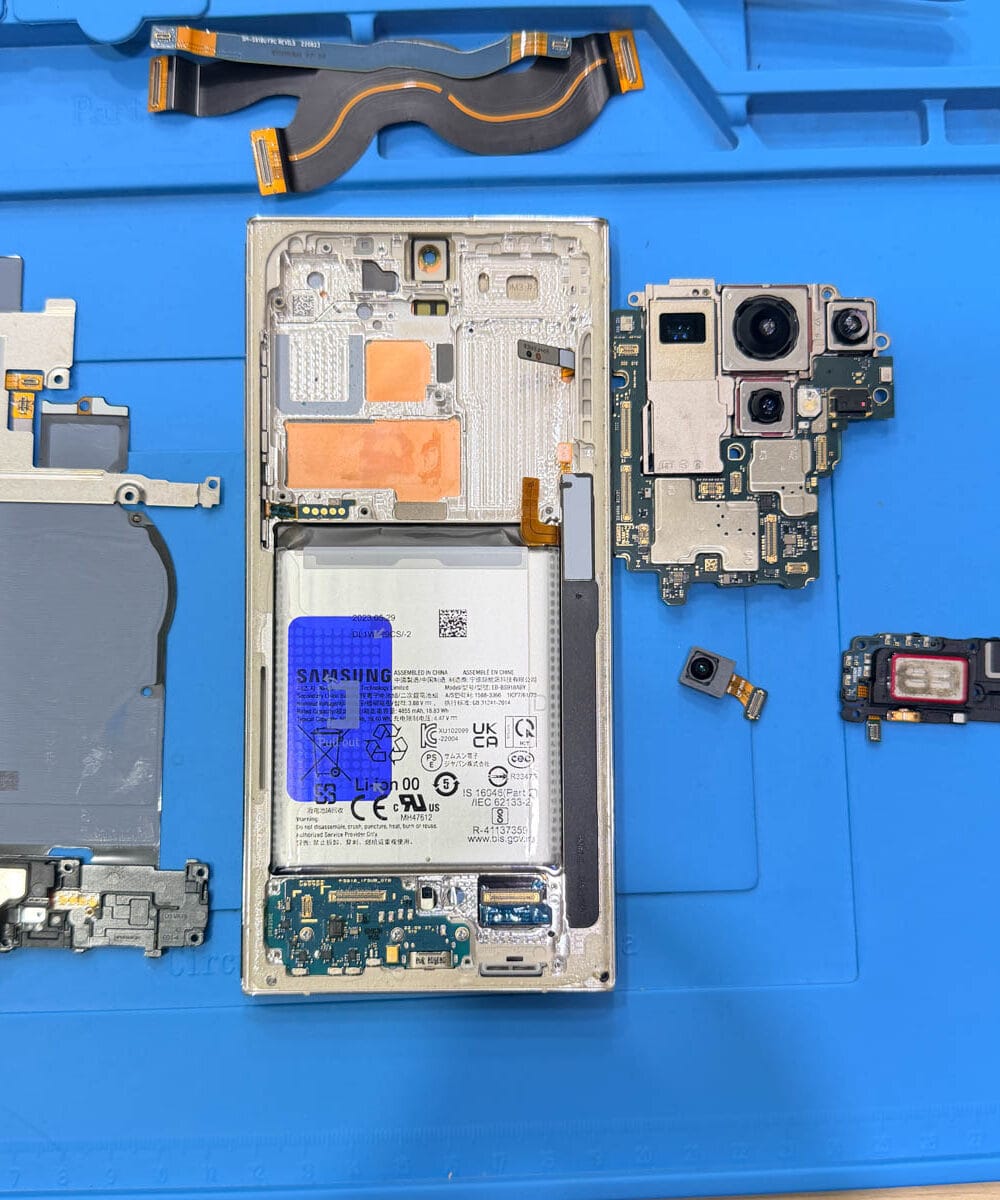 Disassembled Samsung Galaxy S23 Ultra showing battery motherboard and internal components
